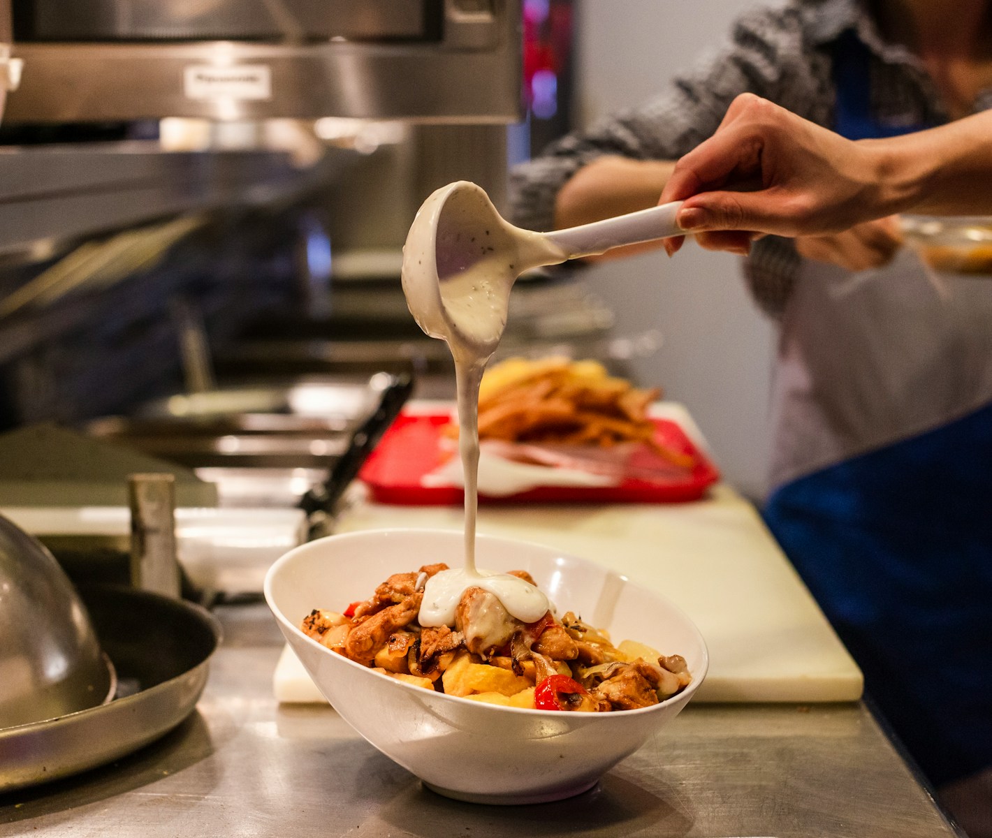 person pouring cream on bowl of food